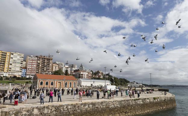 Imagen principal - Una docena de palomas alzaron el vuelo cuando se descubrió la escultura coincidiendo con una parada de velas de los alumnos de la clase óptimis de la Escuela de Vela del Real Club Marítimo. Además, la Banda Municipal tocó 'Santander la Marinera'.