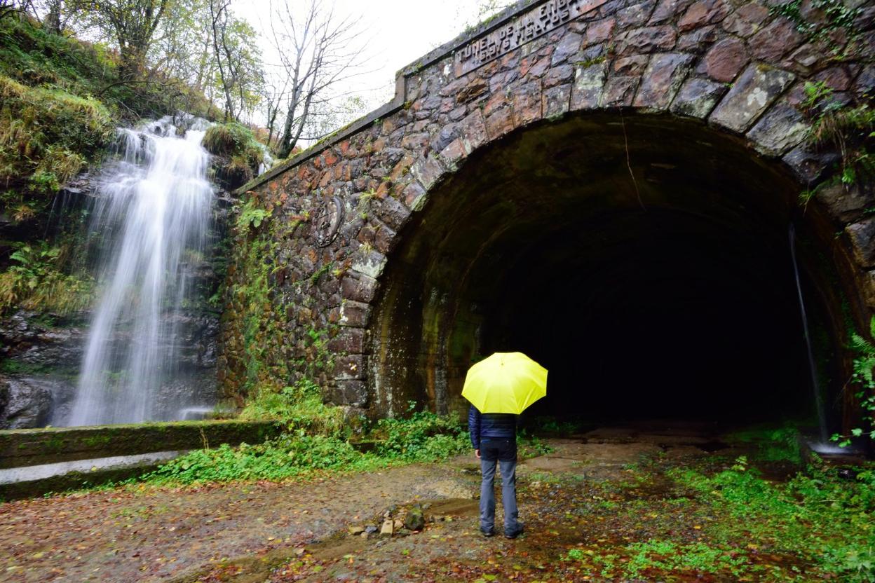 Un senderista observa bajo la lluvia la boca norte del túnel de La Engaña, en el barrio de Yera de Vega de Pas. 