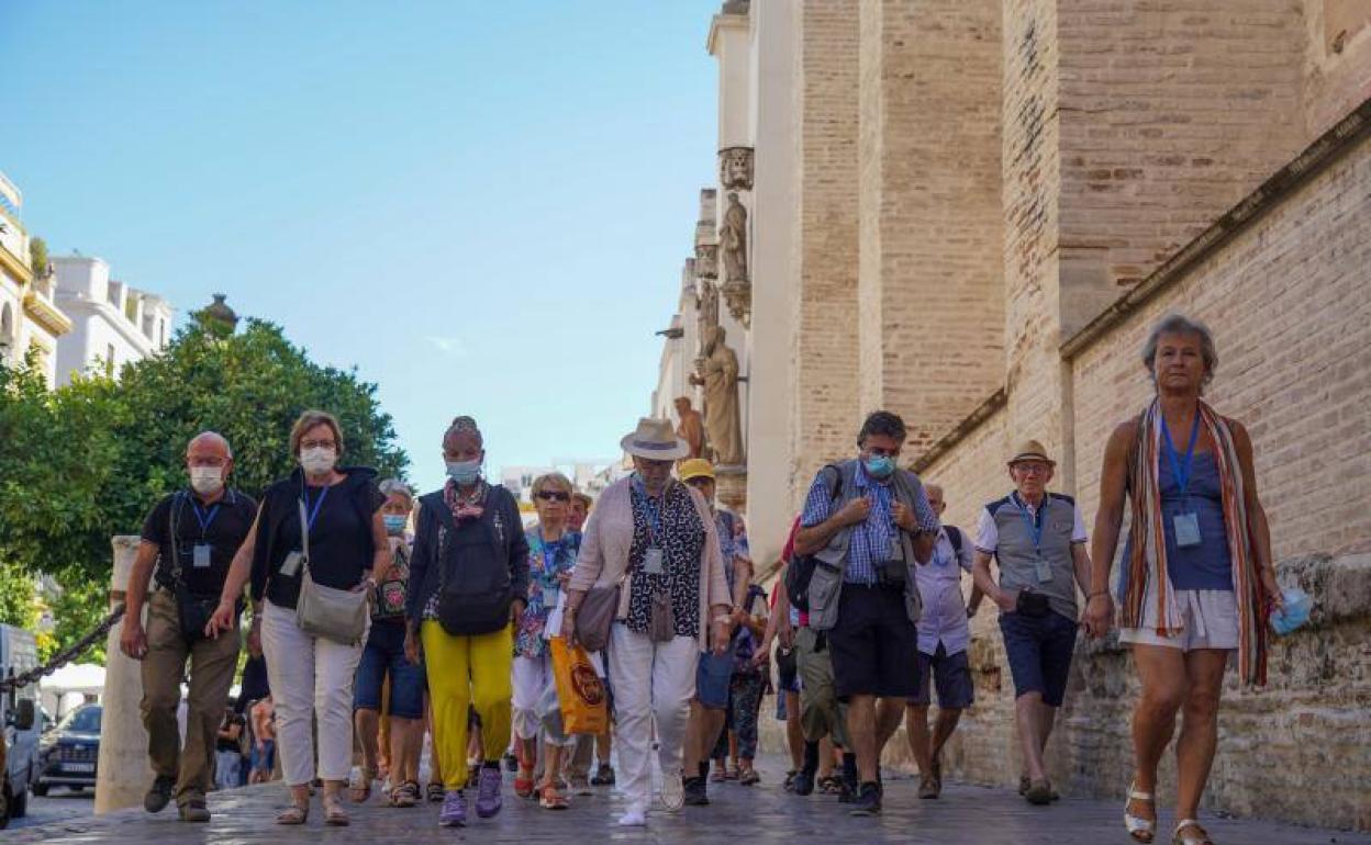 Varias personas pasean por una calle de Sevilla. 