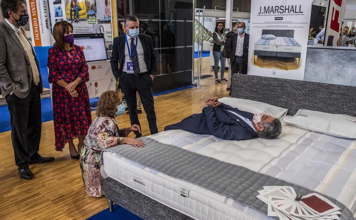 Revilla prueba la comodidad de un colchón en presencia de sus consejeros Gochicoa y Álvarez. 