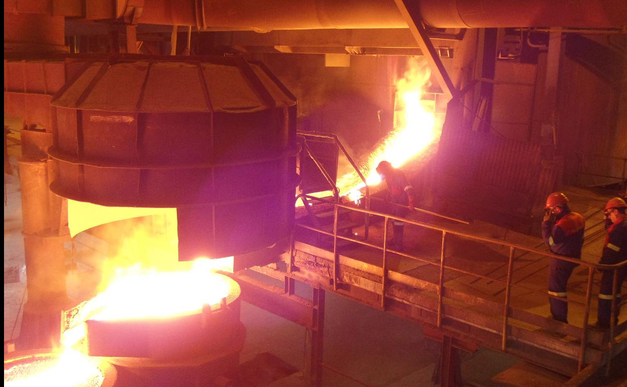 Trabajadores de la empresa Ferroatlántica junto a uno de los hornos de la planta de Boo de Guarnizo. 