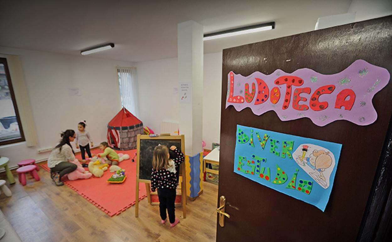 Varios niños juegan en la ludoteca de Comillas acompañados de una dinamizadora sociocultural. 