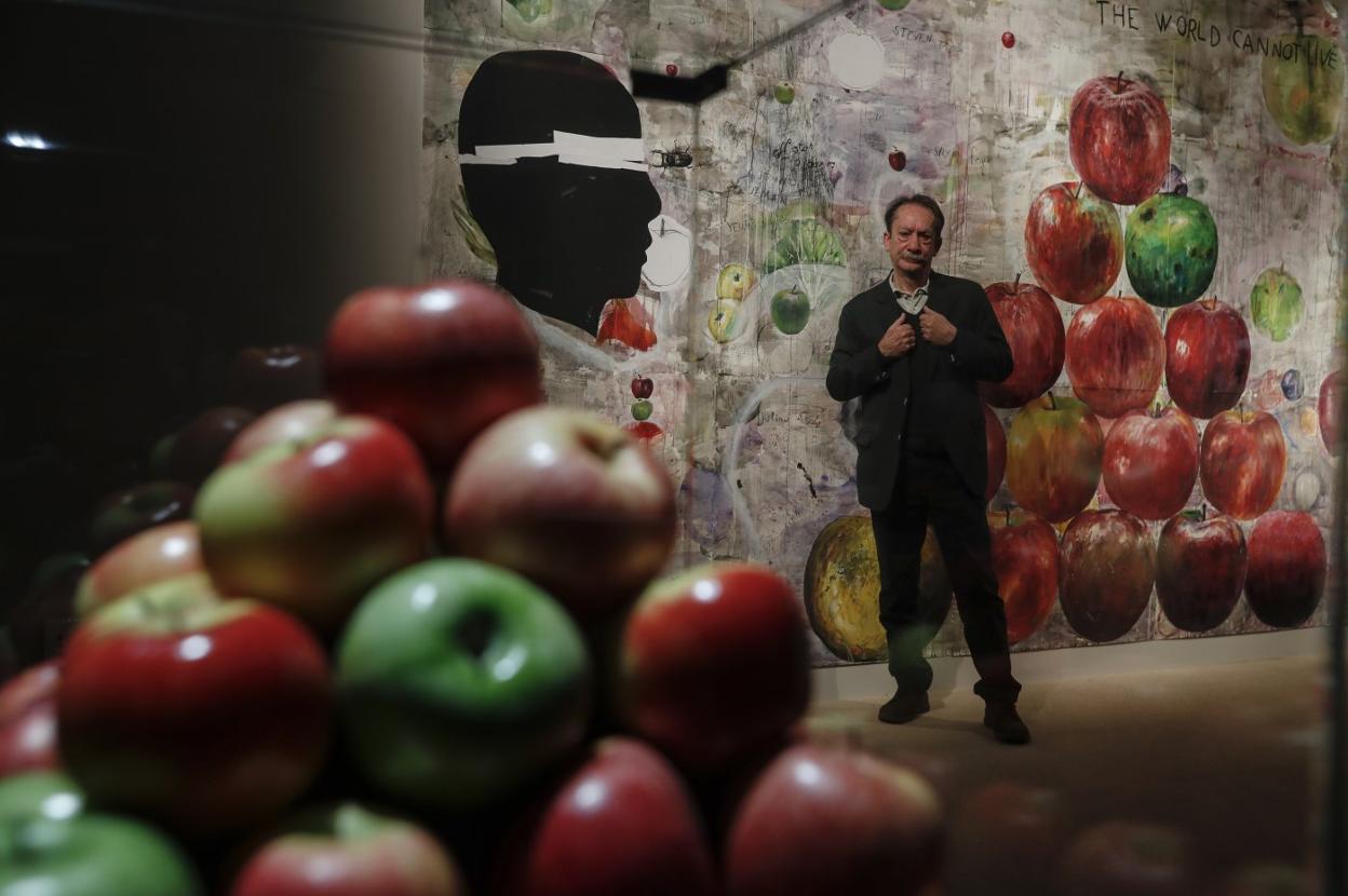 Eduardo Gruber posa entre dos de sus obras, una efímera torre de manzanas y un mural con la misma fruta como protagonista.