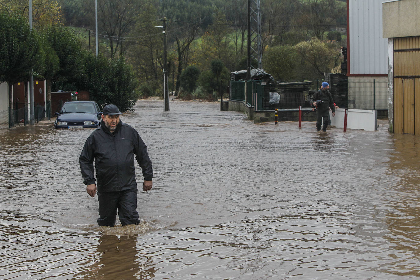 Un hombre cruza una balsa en Vioño, en la que el agua llega por la rodilla.