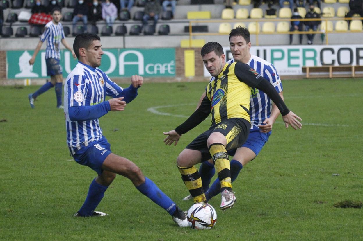 Víctor, del Cayón, protege la pelota ante dos rivales. 