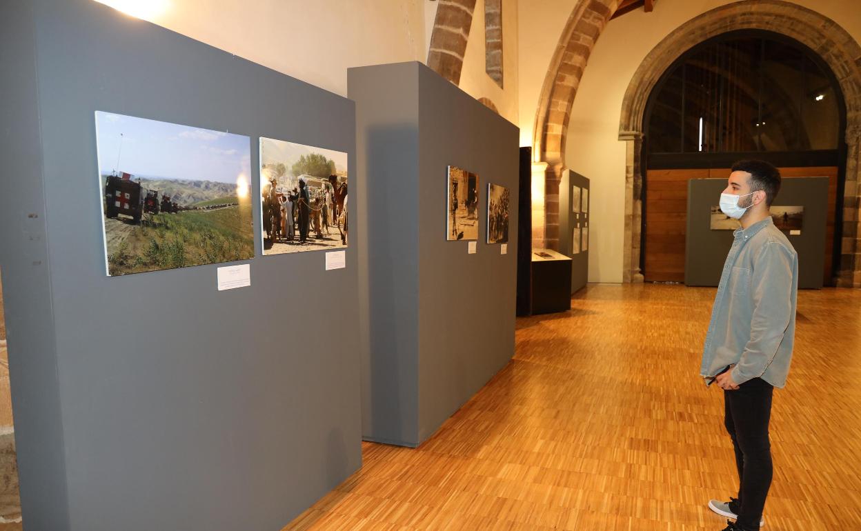 Un joven contempla uno de los paneles de fotografías de la exposición 