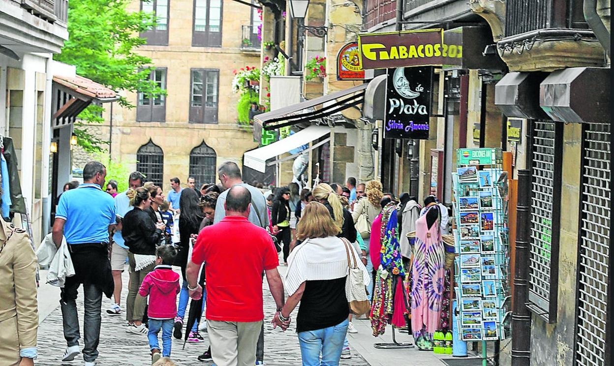 Varias personas atraviesan una de las calles de Comillas donde se concentra buena parte del comercio. 