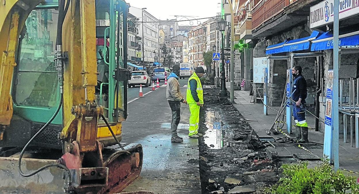 Los operarios trabajan en las obras de construcción de la acera en plena travesía. 