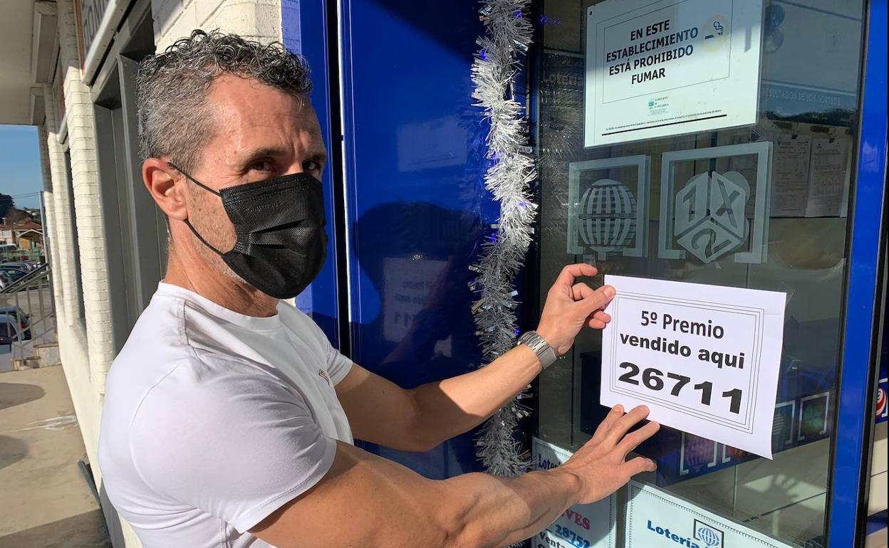 Javier Portilla colgando en la puerta de su administración de Hoznayo el premio.