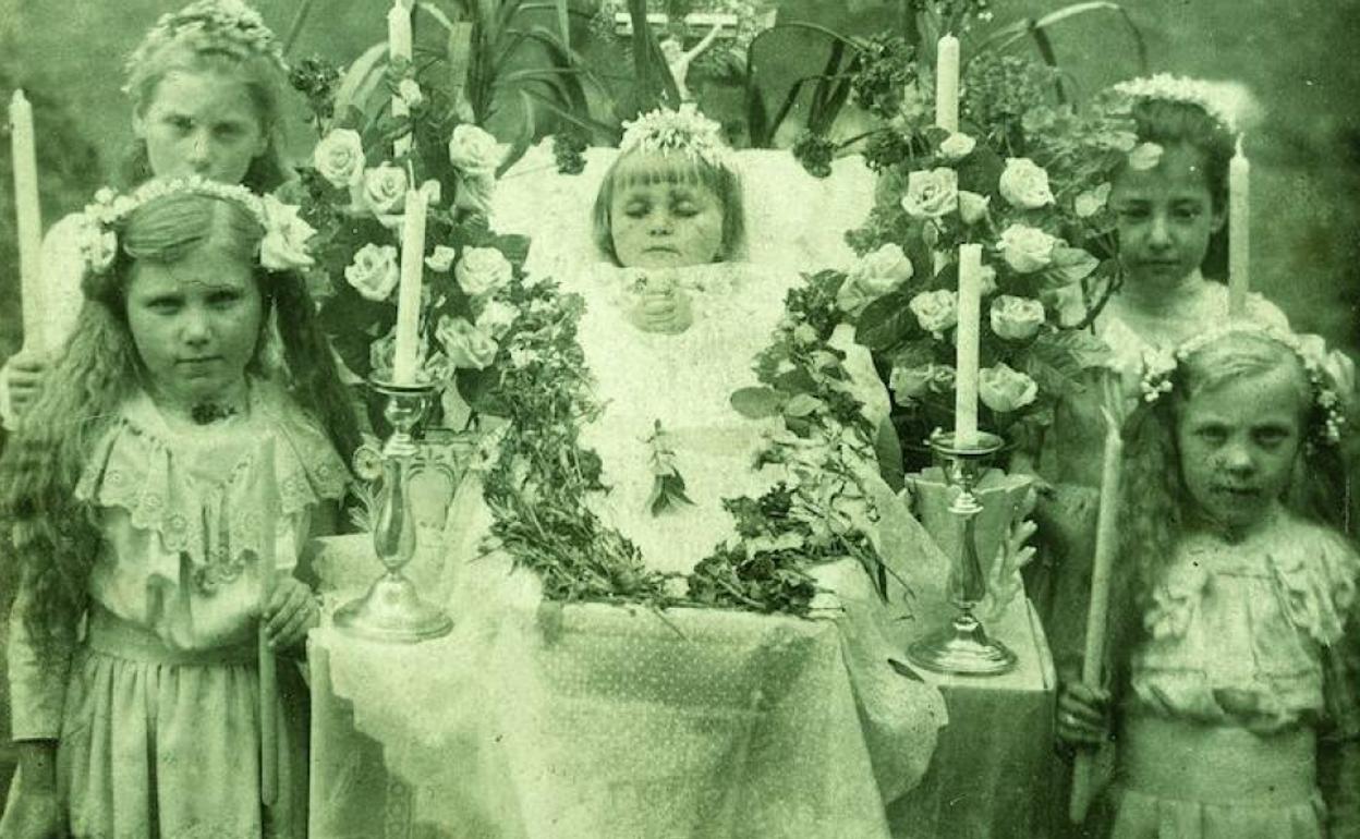 Cuatro niñas velan el cadáver de otra pequeña en una imagen tomada entre 1890 y 1920. 