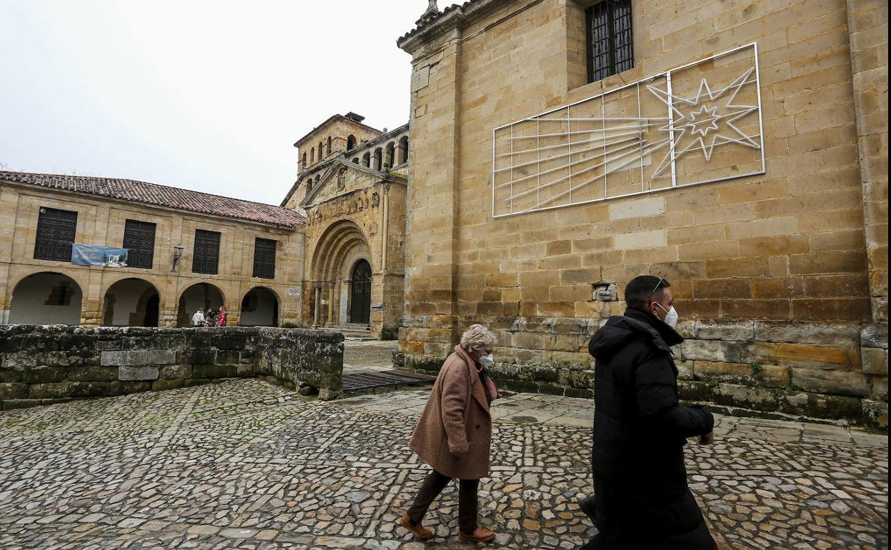 Dos vecinos pasean por delante de la Colegiata junto a la gran estrella colocada en la fachada.