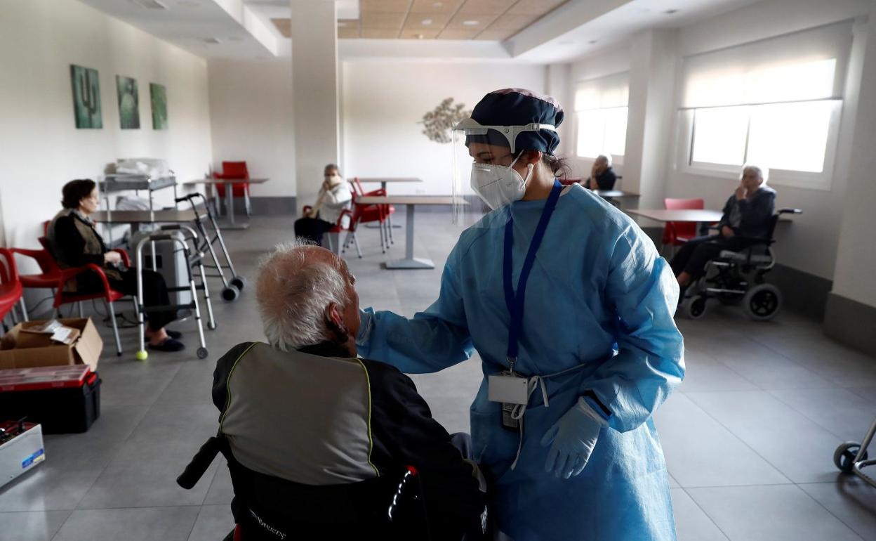 Una sanitaria durante la pandemia atiende a un usuario de la residencia de mayores Casablanca, ubicada en el barrio madrileño de Villaverde.