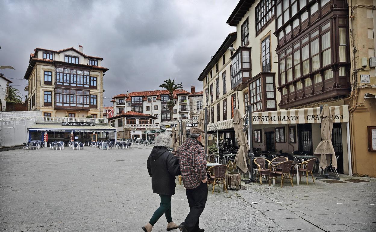 Una pareja pasea por la plaza del corro Campíos de Comillas. 