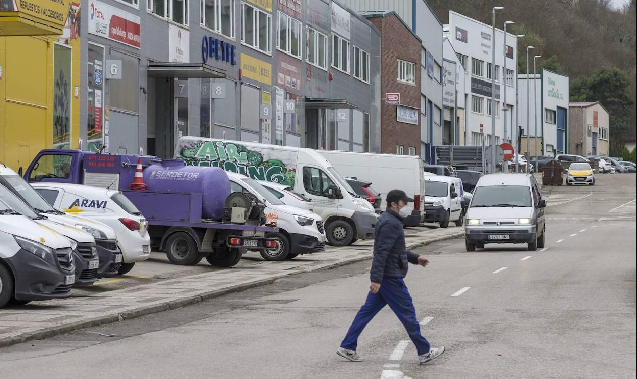 Un vecino cruza la calle en la entrada hacia el polígono de Trascueto, donde se ubican un centenar de empresas en Revilla de Camargo. 