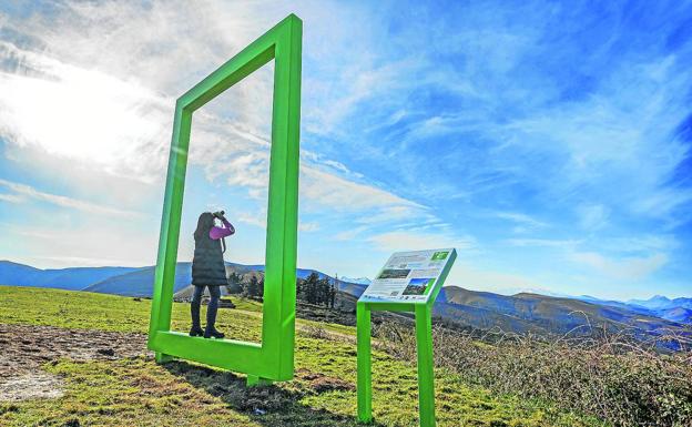 Una mujer observa el paisaje subida a uno de los marcos gigantes instalados en Cabuérniga y Villacarriedo por el Ejecutivo regional. 