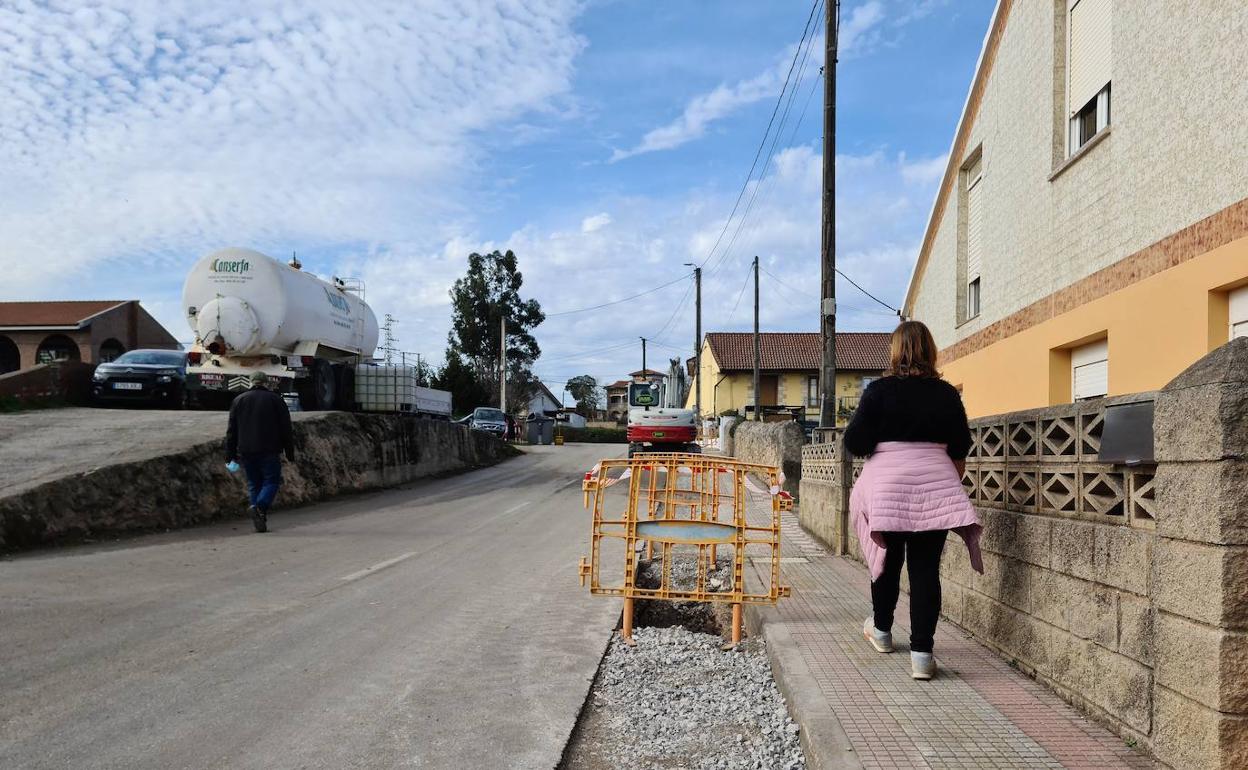 Una vecina de Muriedas camina por la acera de la calle Los Coteros, donde se desarrollan los trabajos en la red de abastecimiento, este jueves, en Camargo.