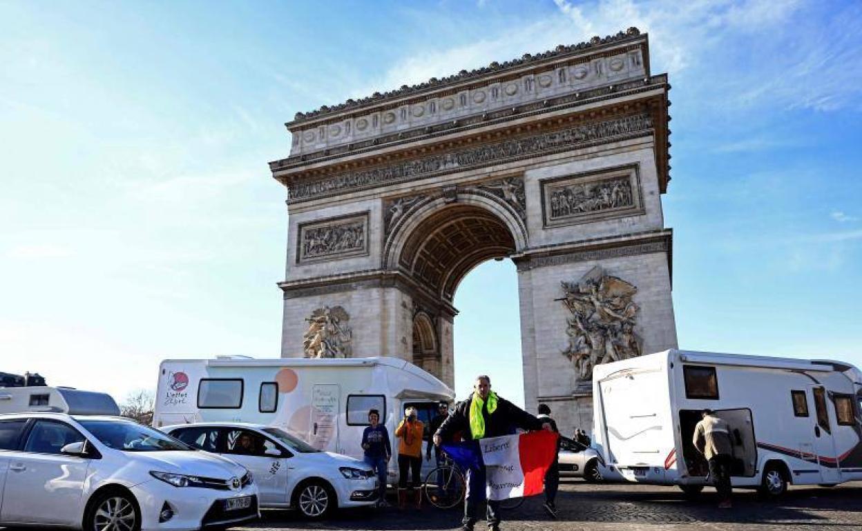 Un hombre muestra una bandera francesa y un chaleco amarillo durante las protestas en París. 