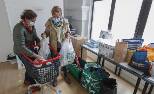 Iris Ruiz y Pilar Calcedo depositan la compra en el centro cívico Callealtero, en la calle Alta. 