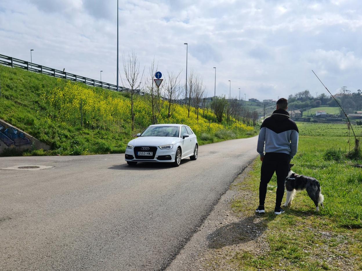 Un vecino y su mascota aguardan ante el avance de un vehículo, este lunes, en el barrio La Calva de Revilla. 