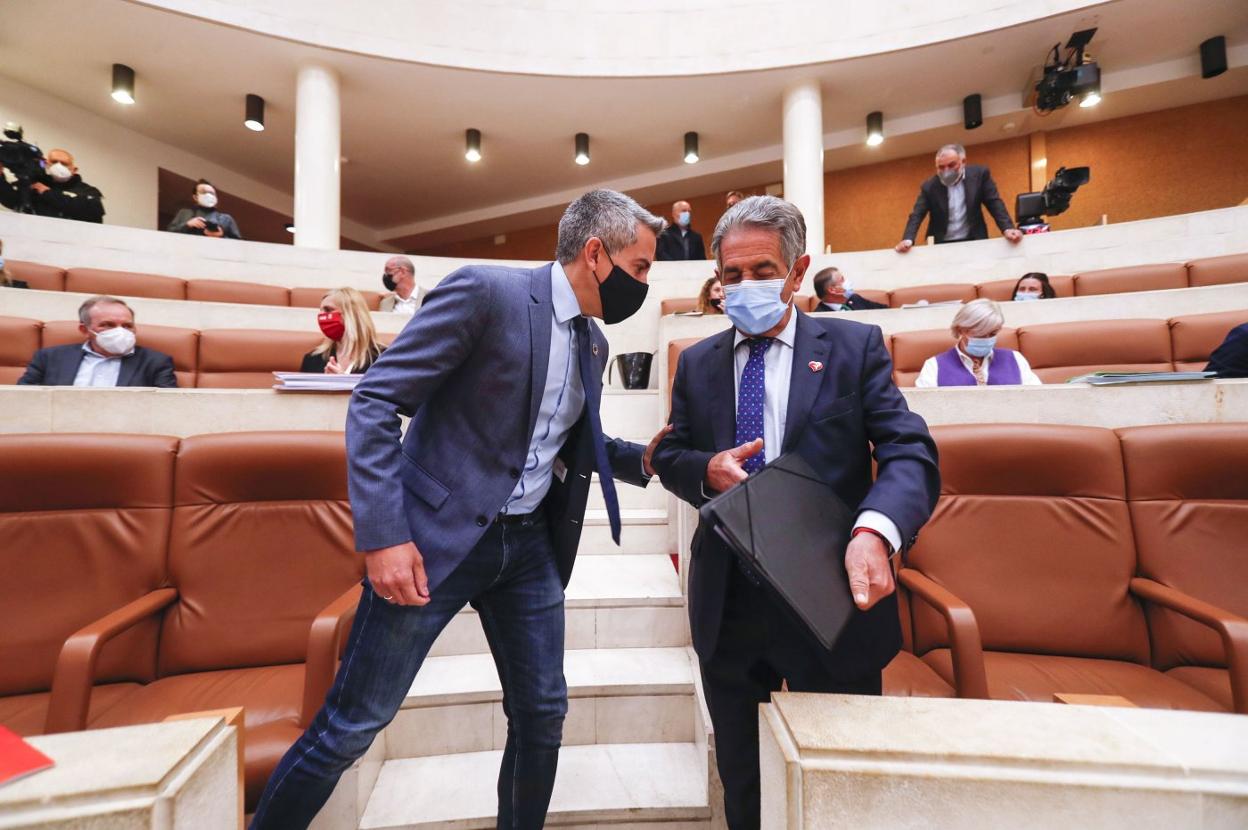 Pablo Zuloaga y Miguel Ángel Revilla conversan en el hemiciclo del Parlamento de Cantabria. 