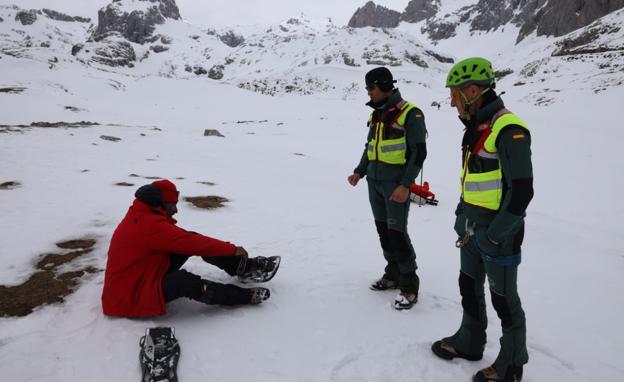 Dos efectivos del Greim, junto al hombre al que han estado buscando, sentado, de rojo.