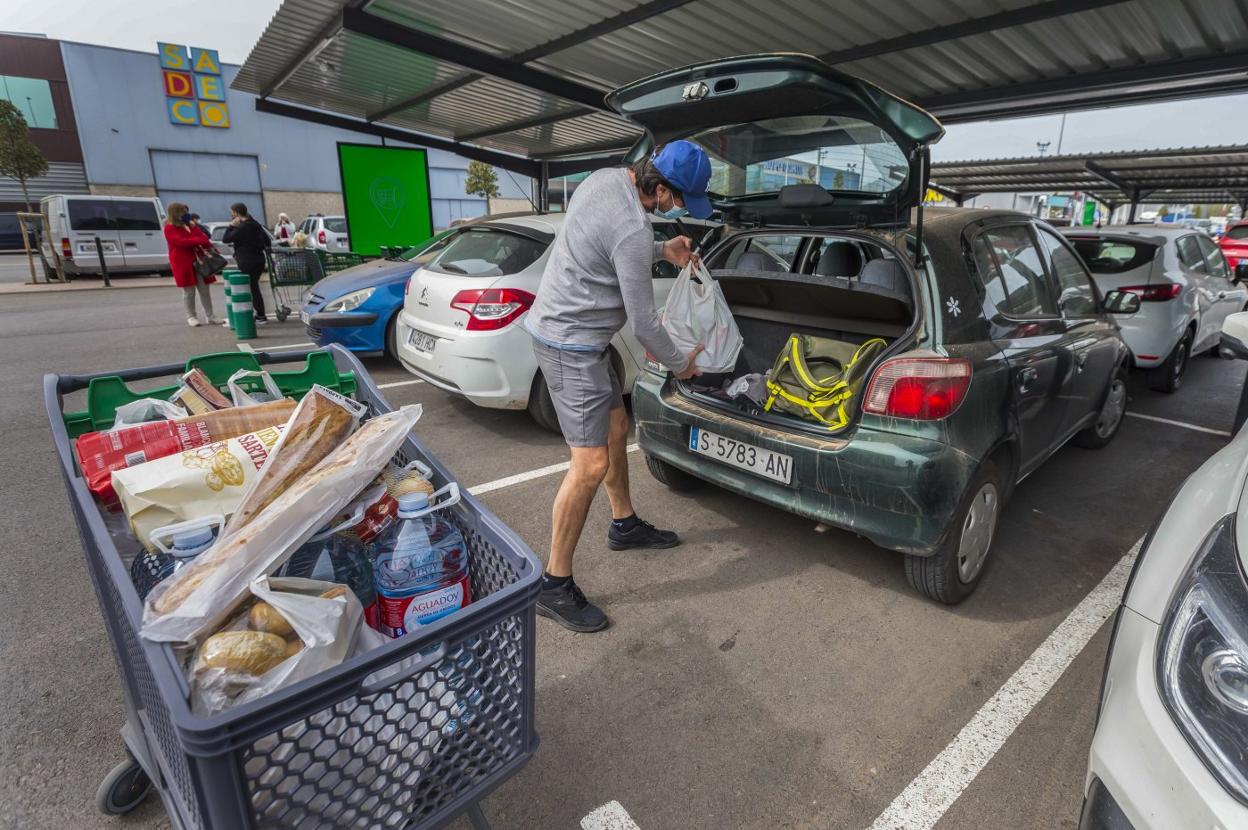 A la compra. Un joven carga la compra del día en el maletero de su vehículo, ayer, en Maliaño. 