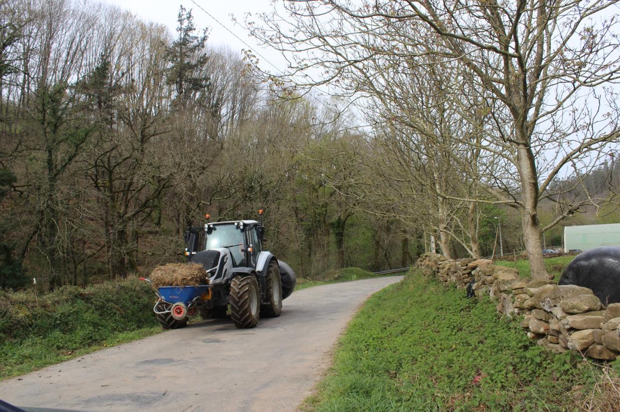 Un tractor pasa por la carretera de Pisueña que está muy deteriorada.