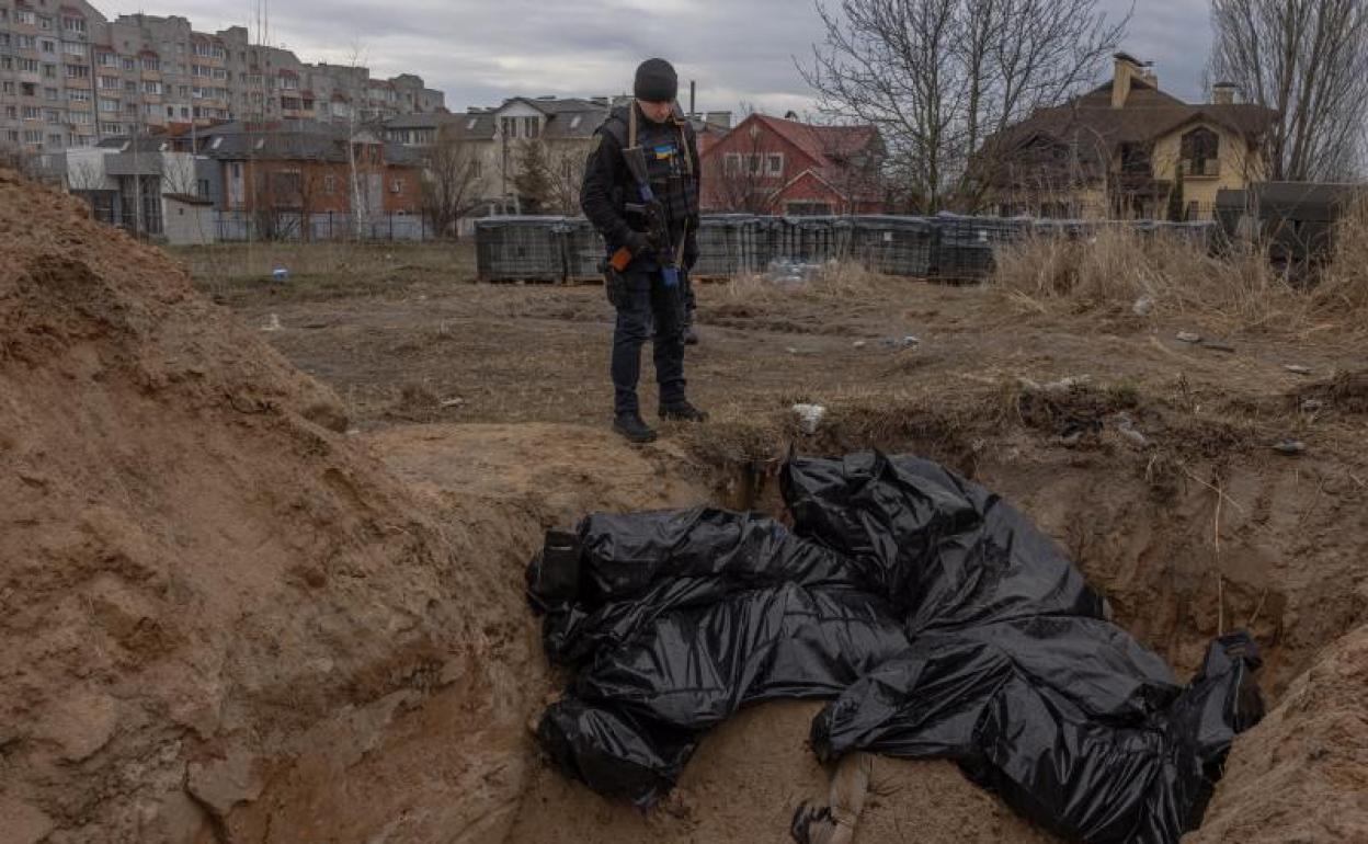 Un hombre observa bolsas que contienen cadáveres de civiles en Bucha.