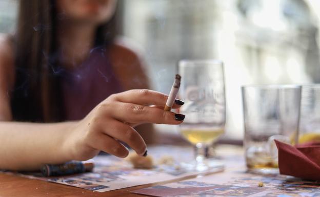 Una mujer fuma un cigarrillo en una terraza de un bar en Bilbao.