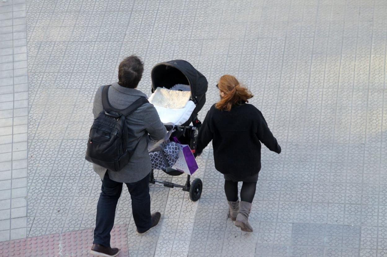 Una pareja camina con su bebé en un carrito.