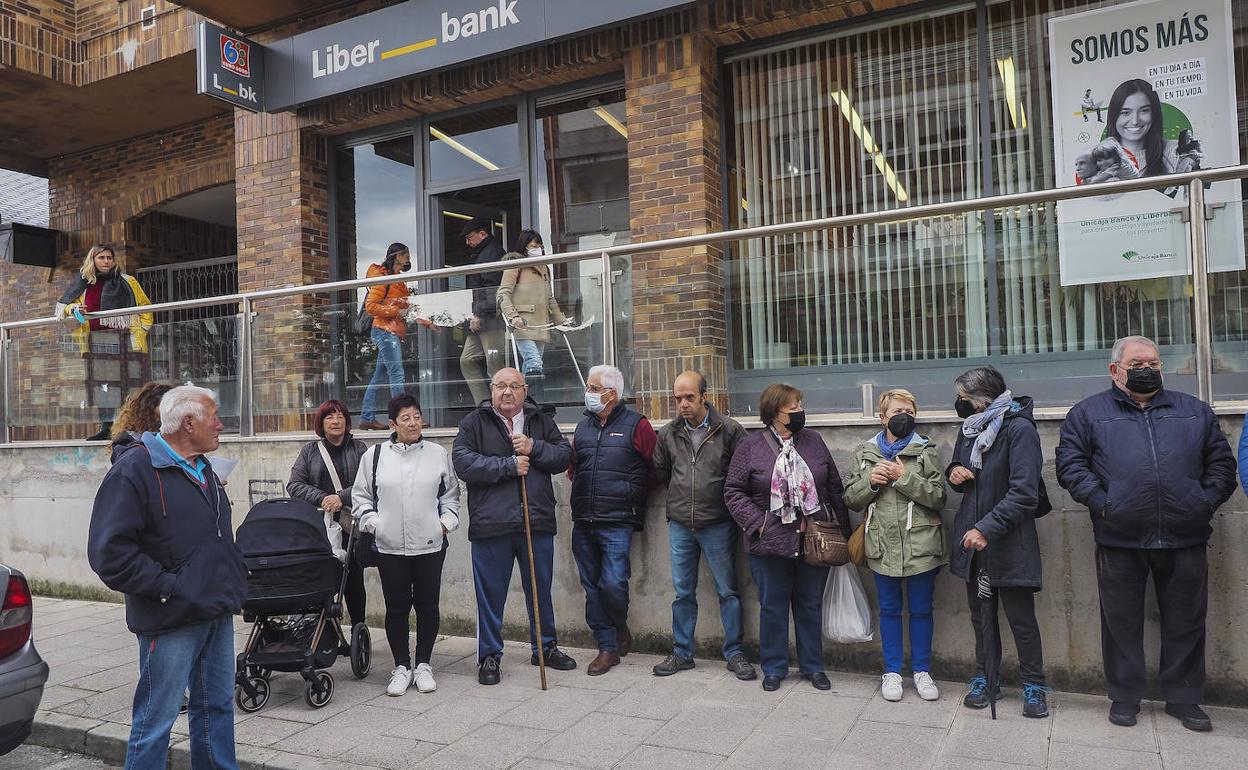 Un grupo de vecinos de Somo se manifestó ayer frente a la sucursal de Unicaja, que tiene previsto cerrar su servicio al público.