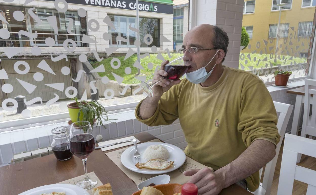 Un hombre bebe una copa de vino en un restaurante. 