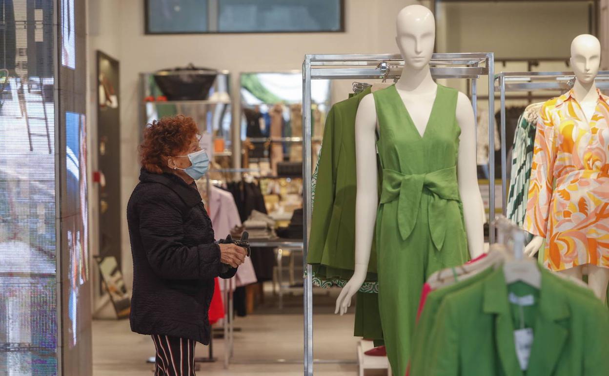 Una mujer mira ropa en una tienda del centro de Santander.