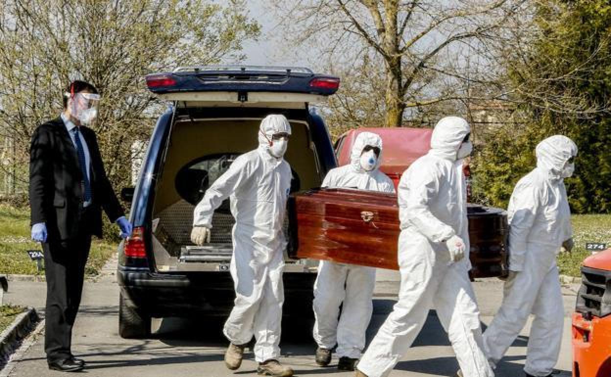 Trabajadores de una funeraria trasladan un féretro. 