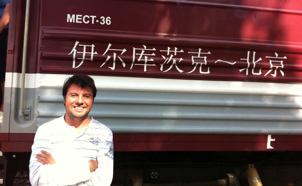 Retrato del autor, el periodista Álvaro Machín, en una estación ante el vagón del tren que recorría el tramo de su viaje por Mongolia. 