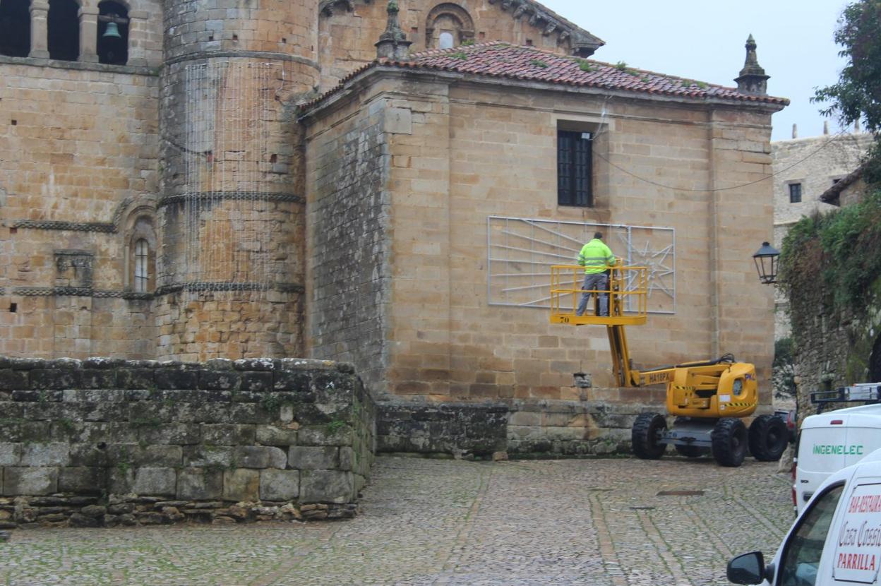 Un operario retira el anclaje de una enorme estrella a la pared de la Colegiata.