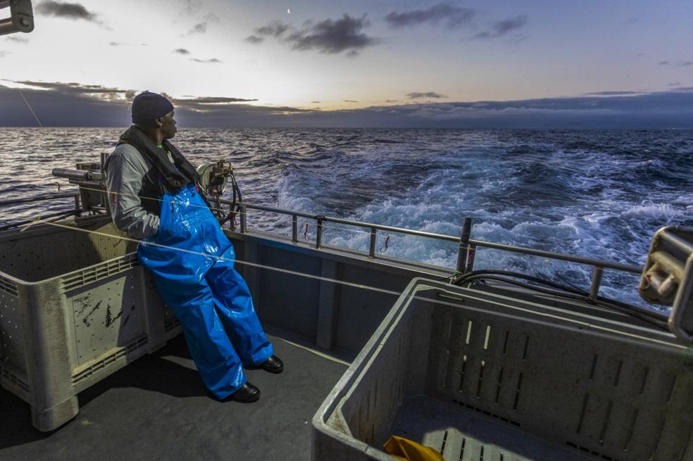 Mamadou Diop, en la popa, al amanecer, durante la travesía hacia el cabezo en el que pescar el verdel.