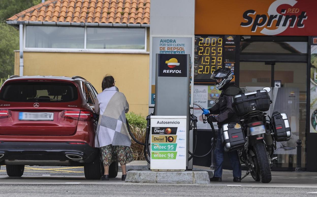 Un motorista y una conductora con con coche repostan en una gasolinera cántabra. 