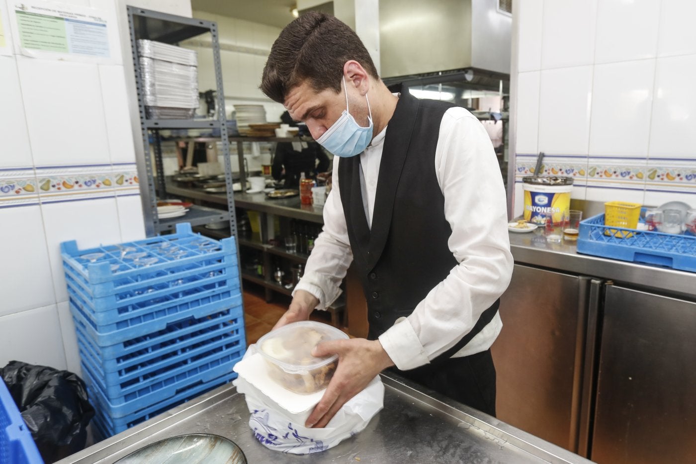 Un trabajador prepara en un envase la comida para llevar. 