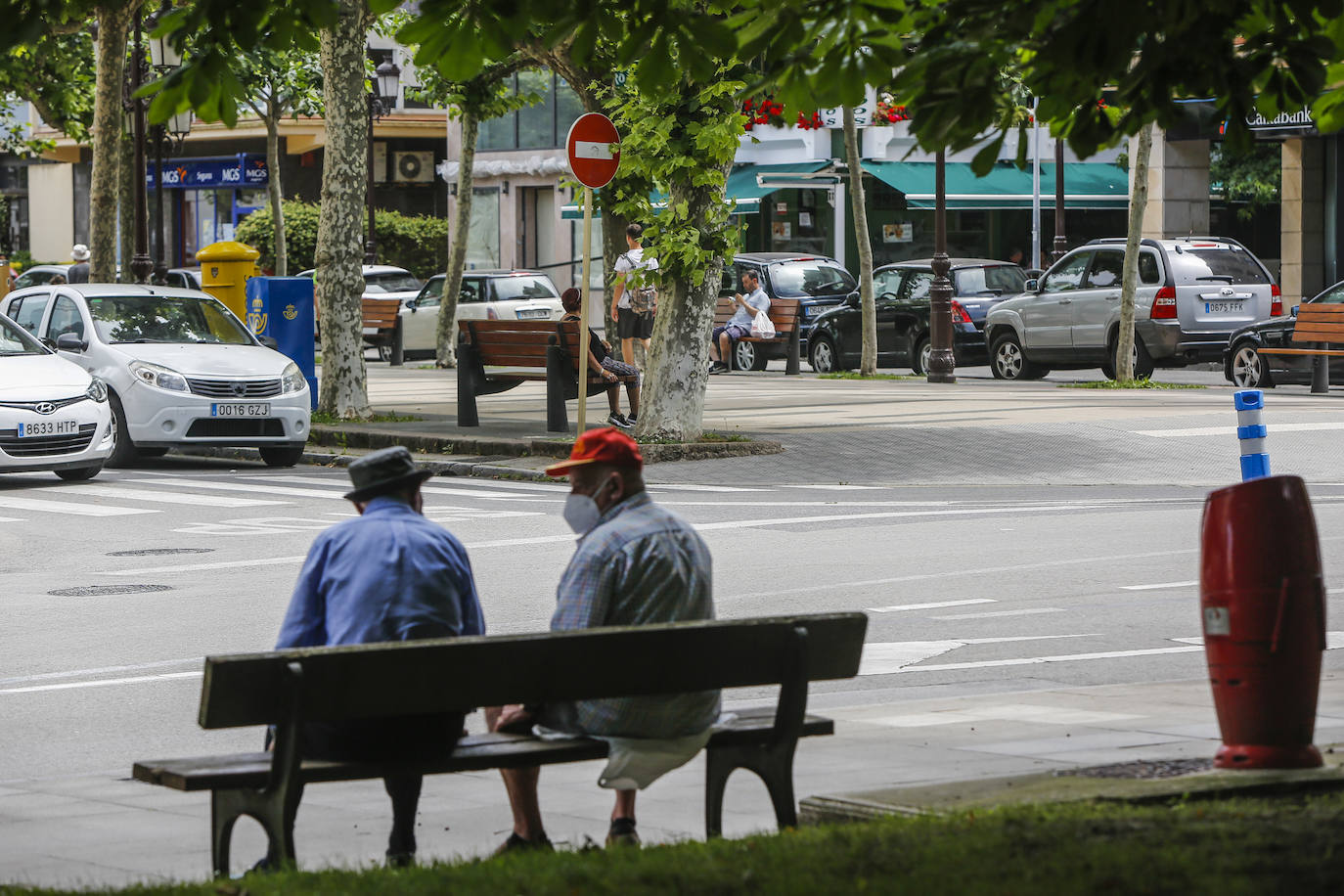 Dos hombres, sentados en un banco en Torrelavega.