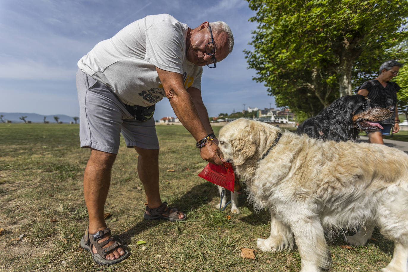 Un hombre da de beber a su perro en la campa de La Magdalena.