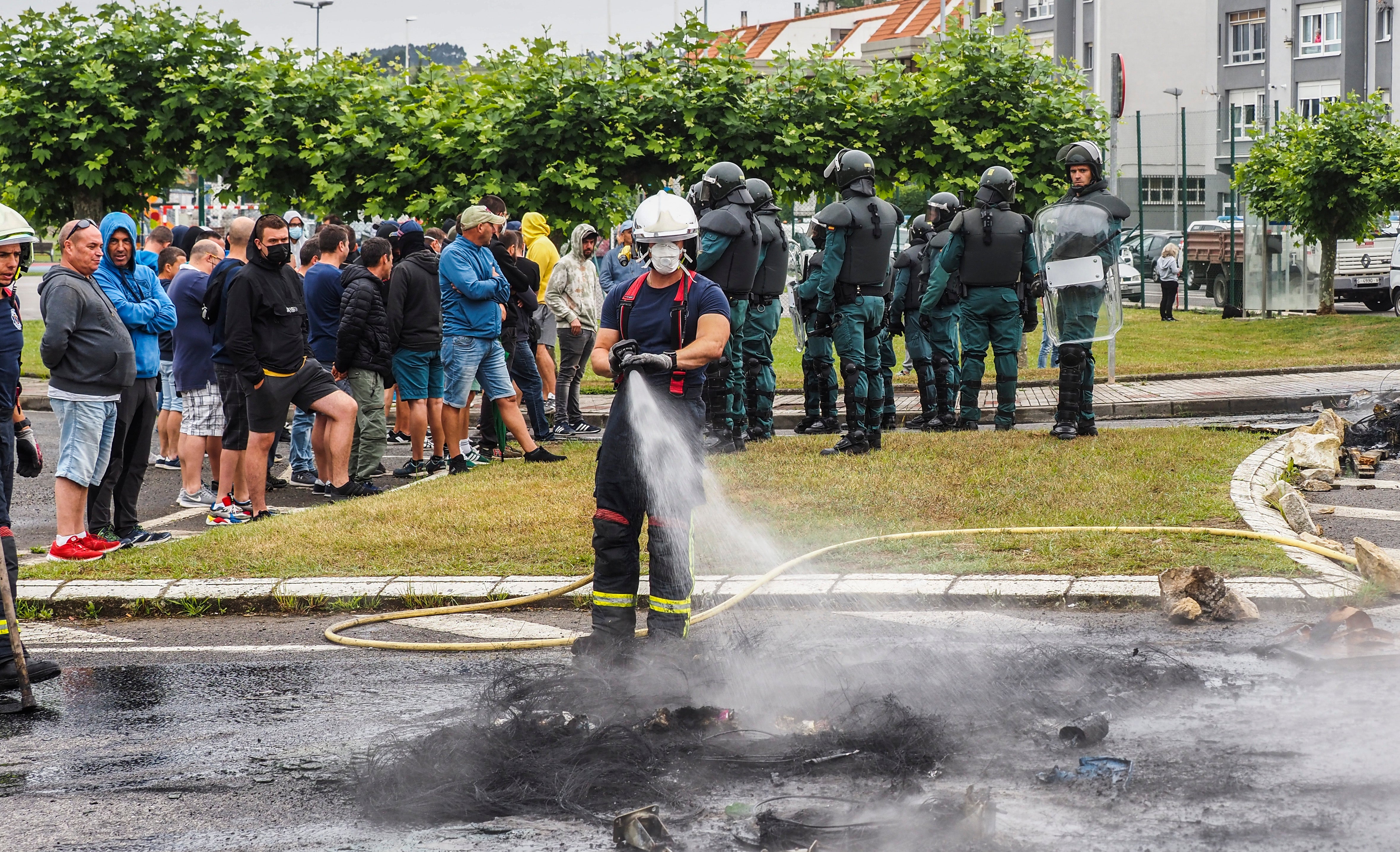 Un bombero apaga el fuego de las barricadas en los accesos a Guarnizo.