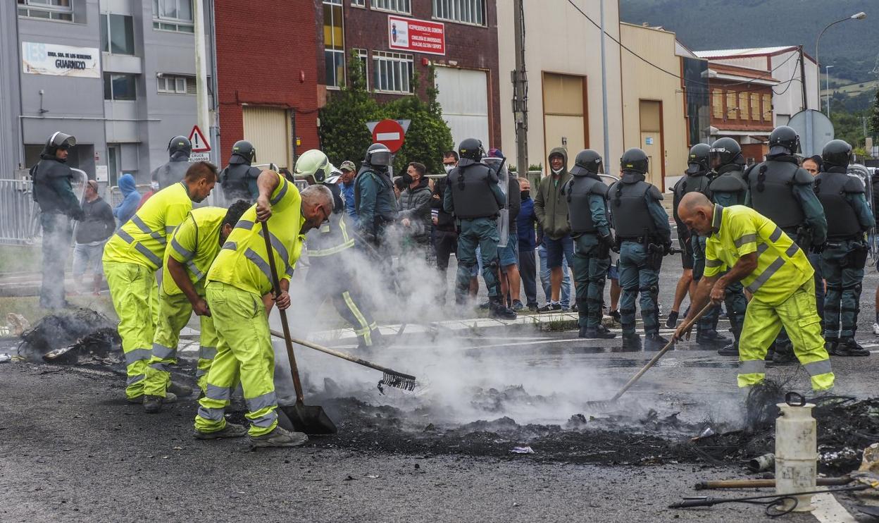 Operarios de limpieza retiran los restos de una barricada en llamas levantada ayer por los huelguistas.