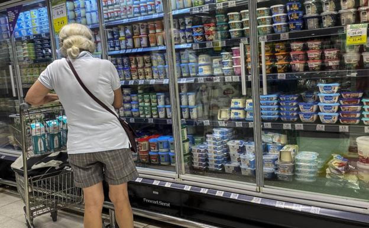 Una clienta observa el expositor de lácteos en un supermercado.