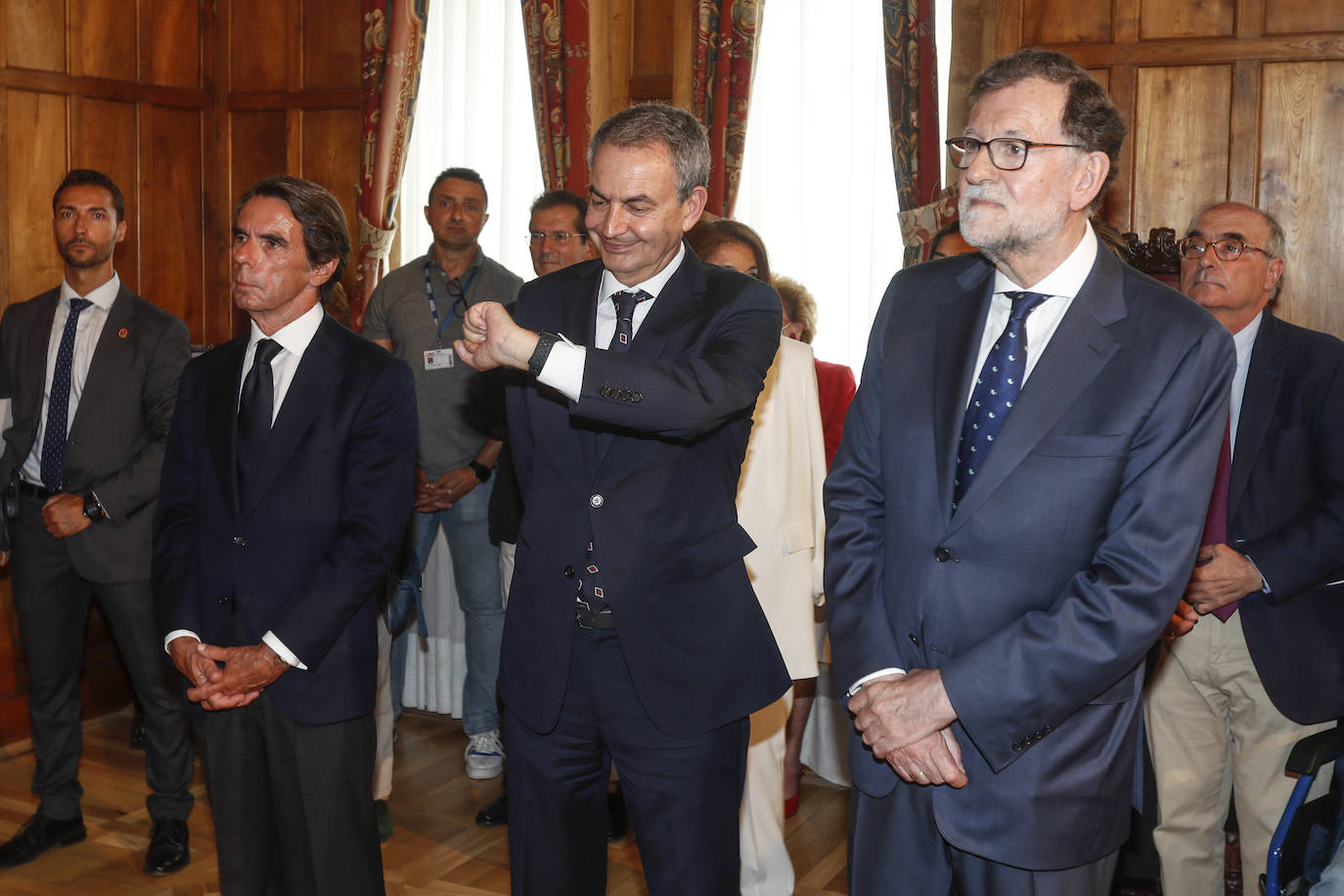 Zapatero (en el centro) mira su reloj, escoltado por Aznar y Rajoy.