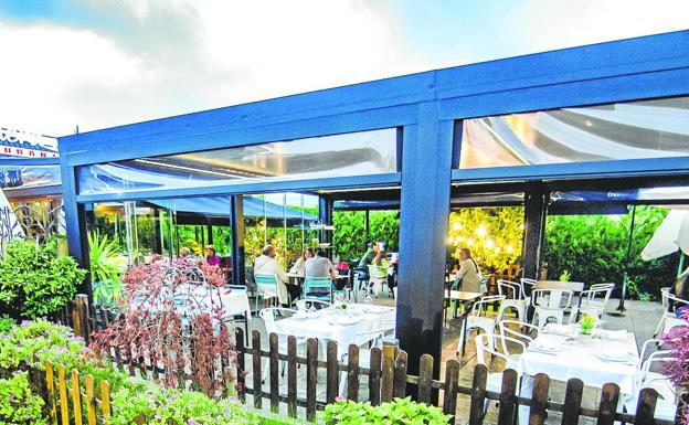 La terraza de este establecimiento se rodea de plantas y cálida iluminación. 