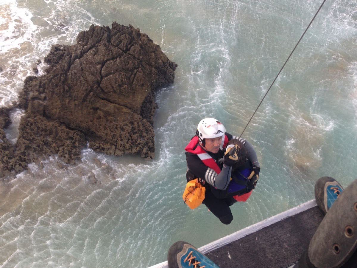 Rescate de un surfista atrapado en unas rocas en una playa de Liencres.