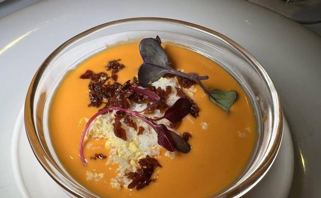 Imagen principal - Arriba, salmorejo con jamón frito y huevo rallado. Abajo, cachón en su tinta con arroz y ensalada de tomate. 