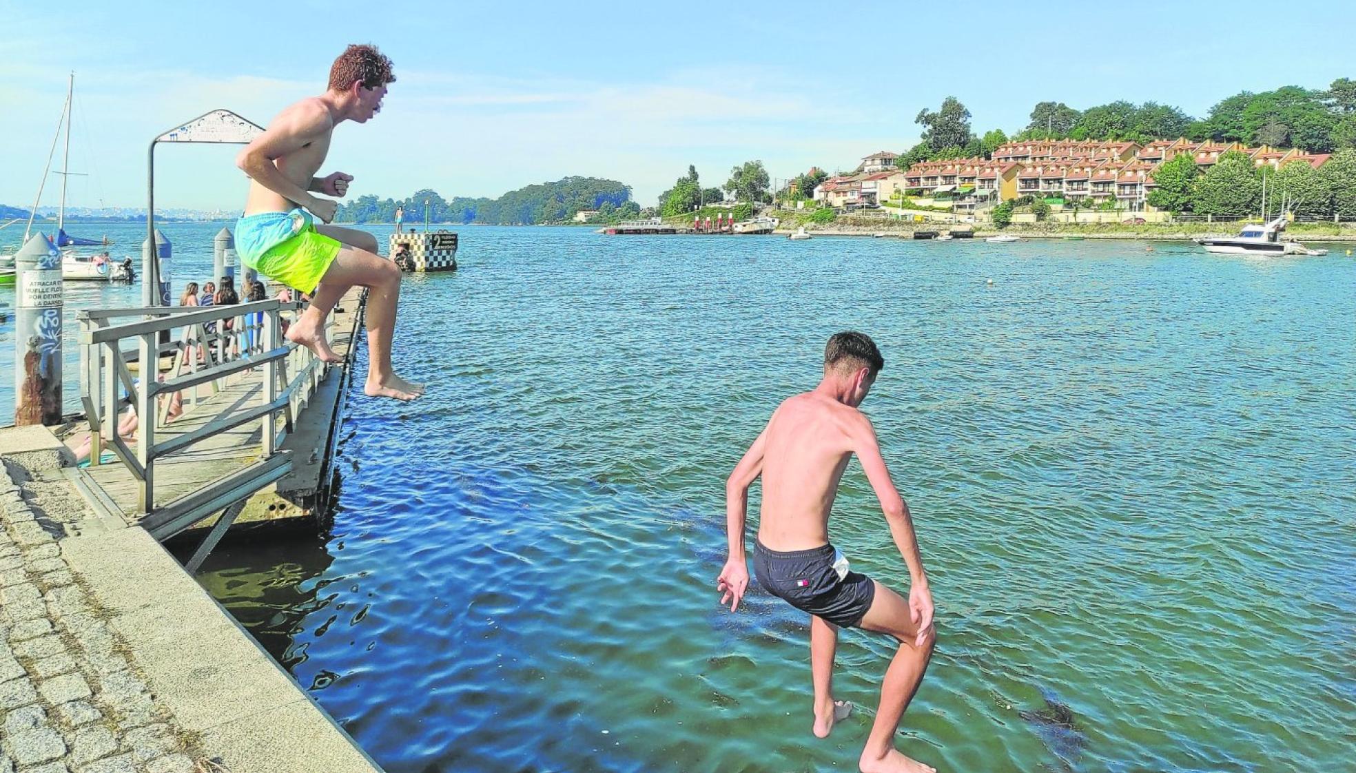 Dos jóvenes se tiran desde el muelle de El Astillero para combatir las altas temperaturas de un día de verano especialmente caluroso.