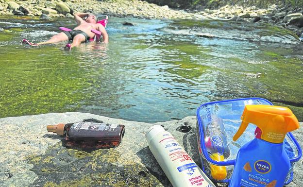 Un bañista combate el sofoco durante la pasada ola de calor remojándose en el río Saja. 